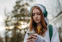 Portrait of teenage girl looking at her smartphone, sad, anxious, alone. Cyberbullying, girl is harassed, threated online.