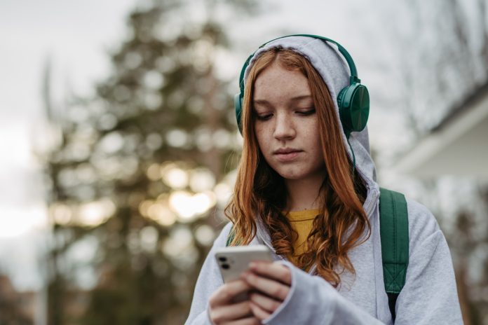 Portrait of teenage girl looking at her smartphone, sad, anxious, alone. Cyberbullying, girl is harassed, threated online.
