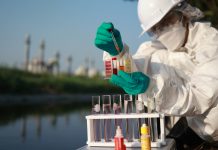 Female scientists wearing Chemical protective suites and PPE collect samples of toxic water to test by mobile lab test, examining wastewater from Industrial, and environment