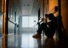Doctor, stress and woman with depression, burnout and tired in hospital for medical news. Nurse, anxiety and female person with mental health, headache and sad sitting on floor for patient death
