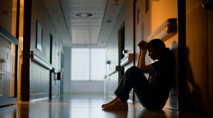 Doctor, stress and woman with depression, burnout and tired in hospital for medical news. Nurse, anxiety and female person with mental health, headache and sad sitting on floor for patient death
