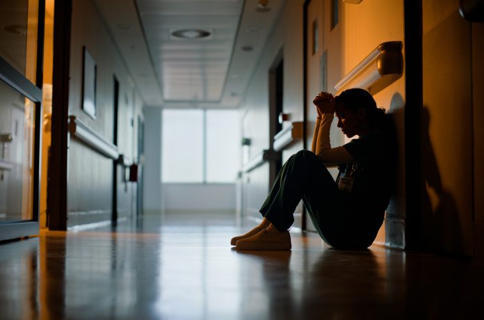 Doctor, stress and woman with depression, burnout and tired in hospital for medical news. Nurse, anxiety and female person with mental health, headache and sad sitting on floor for patient death