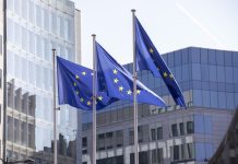 EU flags outside a modern office building in Brussels