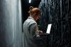 IT specialist working on a laptop in a server room