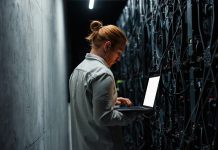 IT specialist working on a laptop in a server room
