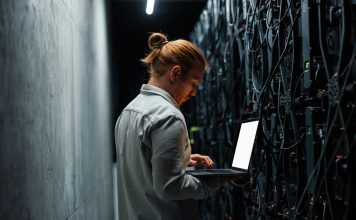 IT specialist working on a laptop in a server room