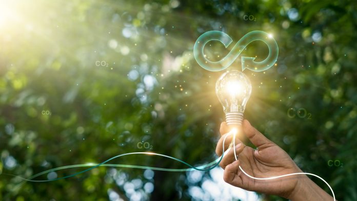 Circular economy. Hand hold light bulb with circular icon. Energy consumption and CO2 emissions, reusing and recycling existing materials for future growth of business and environment sustainable.
