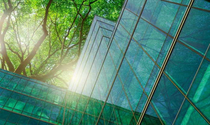 Sustainble green building. Eco-friendly building in modern city. Sustainable glass office building with tree for reducing carbon dioxide. Office with green environment. Corporate building reduce CO2.