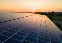 Blue photovoltaic solar panels mounted on building roof for producing clean ecological electricity at sunset. Production of renewable energy concept.