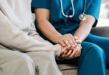 A female nurse caregiver holds hands to encourage and comfort an elderly woman. For care and trust in nursing homes for people of retirement age Caregiver helping elderly woman provides medical advice
