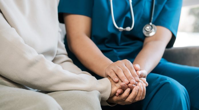A female nurse caregiver holds hands to encourage and comfort an elderly woman. For care and trust in nursing homes for people of retirement age Caregiver helping elderly woman provides medical advice