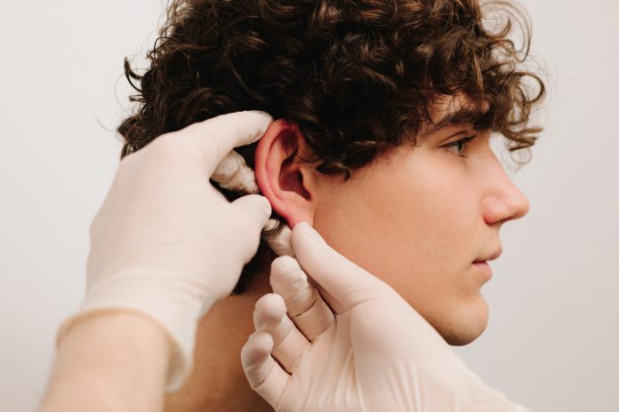Process of examination patient before otoplasty surgery. Surgeon doctor makes palpation before cosmetic ear surgery.