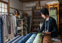 Mature woman inspecting the finished textile fabric she designed after manufacturing