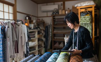 Mature woman inspecting the finished textile fabric she designed after manufacturing