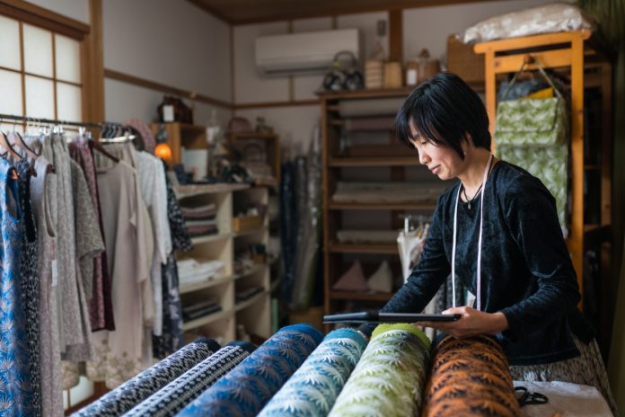 Mature woman inspecting the finished textile fabric she designed after manufacturing