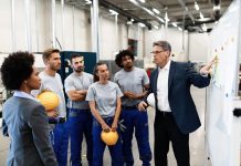 Corporate manager giving a presentation to group of factory workers and talking with them about future business development.