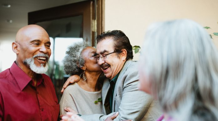 friends greeting each other at door with social kiss on cheek
