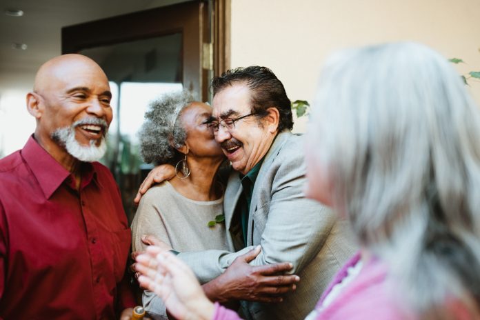 friends greeting each other at door with social kiss on cheek