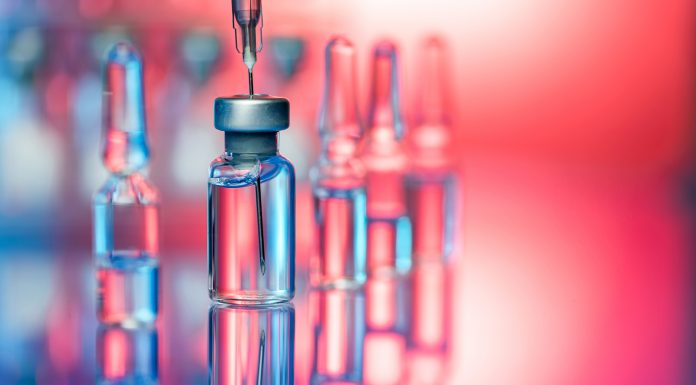 Close up shot of vaccines - glass bottles, ampules and syringe with needle. Good for illustration of flu shot, vaccination and covid-19