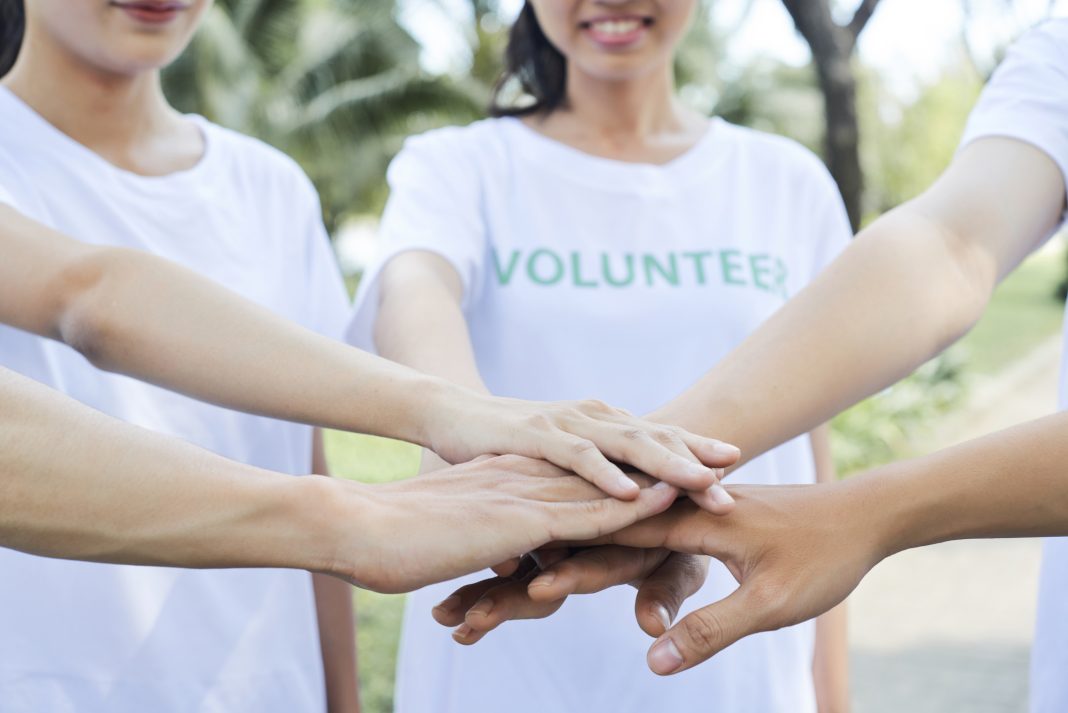Close-up image of volunteers stacking hands to express support and unity before starting work
