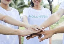 Close-up image of volunteers stacking hands to express support and unity before starting work