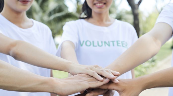 Close-up image of volunteers stacking hands to express support and unity before starting work