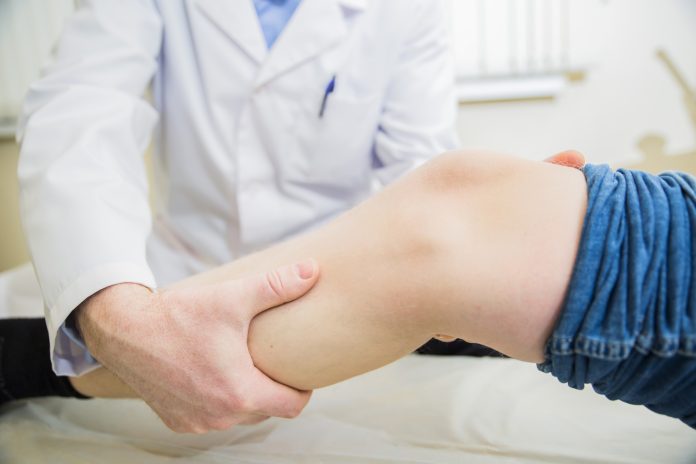 closeup doctor the traumatologist examines the patient the patient's ankle leg