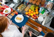 A high angle view of a young teenage girl who is looking at the options for her lunch in the school she goes to in the North East of England. There is plenty of choice of fresh fruit and snacks to choose from in the chiller cabinet.