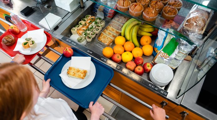 A high angle view of a young teenage girl who is looking at the options for her lunch in the school she goes to in the North East of England. There is plenty of choice of fresh fruit and snacks to choose from in the chiller cabinet.