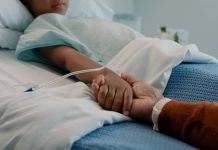 Hospital, holding hands and kid in bed with love, support and care in clinic after surgery. Child, healthcare and cancer patient with empathy, kindness and caregiver with compassion with help