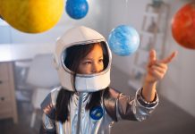 Girl in a space suit playing at home, exploring and learning about planets, imagining space travel.
