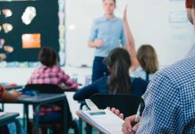 Male Trainee Teacher Being Observed Teaching In Classroom By Supervisor