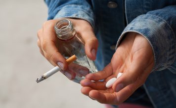 Girl holding vodka,pills and cigarettes