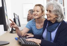 Tutor Helping Senior Woman In Computer Class