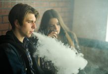 Tackling youth vaping: Current regulations fall short and new tech offers effective solutions Vape teenagers. Young cute girl in sunglasses and young handsome guy smoke an electronic cigarettes in the vape bar. Bad habit that is harmful to health. Vaping activity.