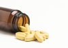 "Vitamin pills spilling from an open bottle, not isolated"