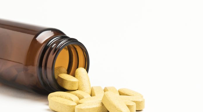 "Vitamin pills spilling from an open bottle, not isolated"
