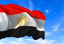 The national flag of Egypt waving in the wind on a blue sky
