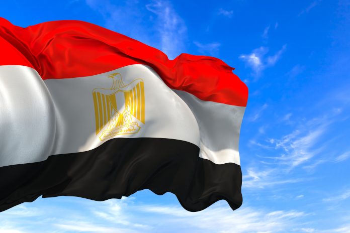 The national flag of Egypt waving in the wind on a blue sky
