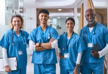 Portrait Of Smiling Multi Cultural Medical Team Wearing Scrubs In Modern Hospital