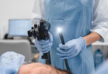 Gastrointestinal fiberoptic endoscopy concept. Cropped close up shot of female doctor holding modern endoscope device before gastroscopy examination with blue protective gloves