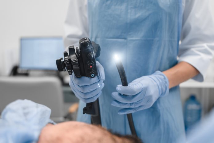 Gastrointestinal fiberoptic endoscopy concept. Cropped close up shot of female doctor holding modern endoscope device before gastroscopy examination with blue protective gloves