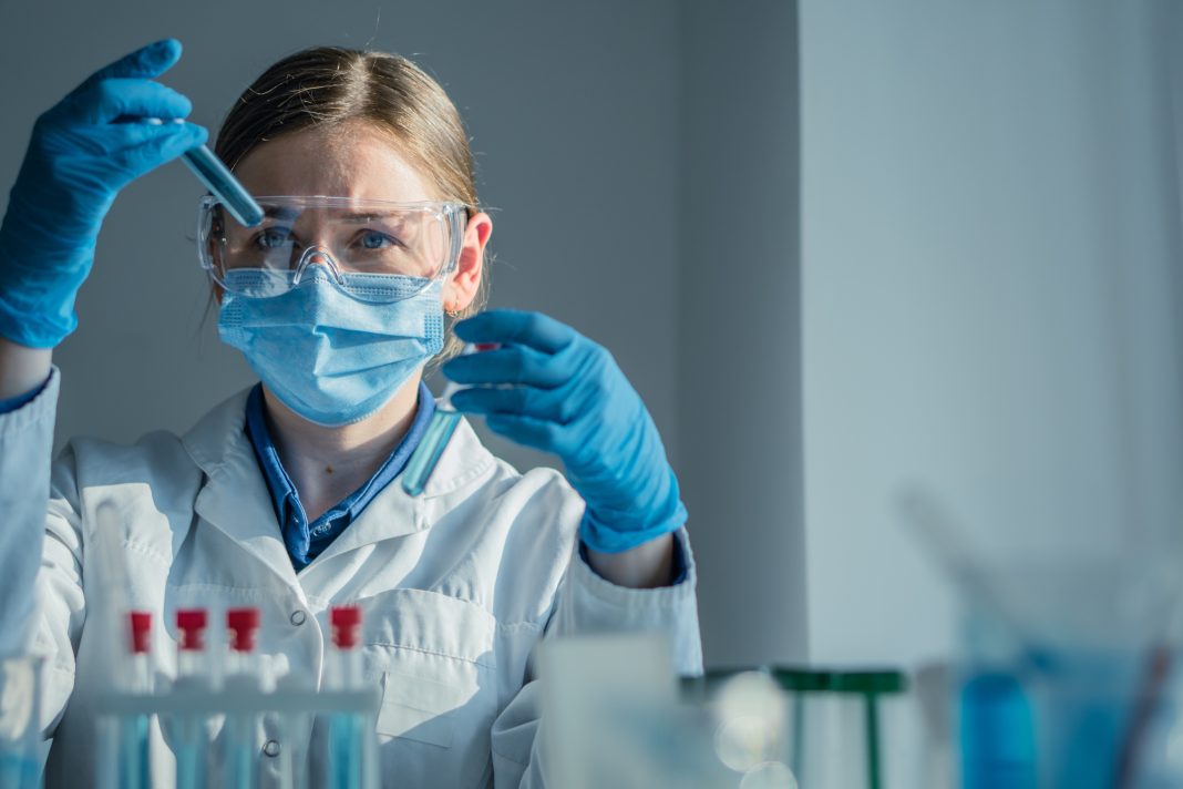 In a hightech lab, a dedicated scientist in a lab coat conducts a complex experiment with a pipette, surrounded by colorful test tubes of reactive substances, showcasing scientific exploration