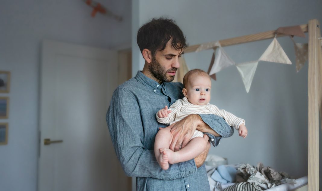 Father on paternity leave looking after his infant son at home