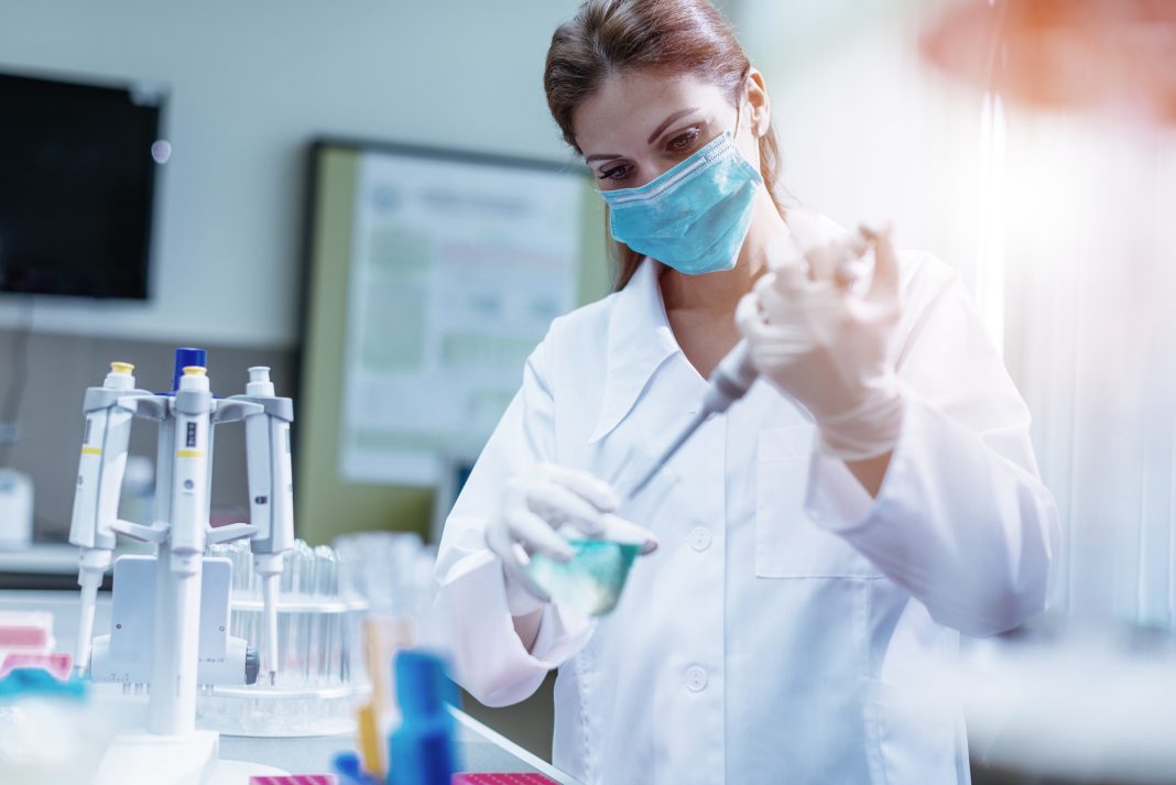 Examining DNA samples in laboratory Woman in laboratory, examining new potions for the scientific research at university. Woman is wearing protective mask and protective gloves (Surgical gloves) while working with beakers, test tubes and other lab equipment. Series of images, taken with Nikon D800 and 50mm or 85 mm professional lens, developed from RAW.