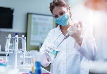 Woman in laboratory, examining new potions for the scientific research at university. Woman is wearing protective mask and protective gloves (Surgical gloves) while working with beakers, test tubes and other lab equipment. Series of images, taken with Nikon D800 and 50mm or 85 mm professional lens, developed from RAW.