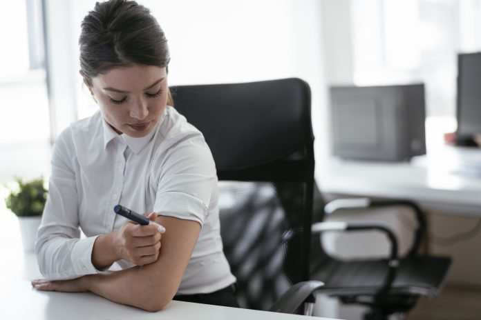 Businesswoman is giving herself an injection of insulin. Businesswoman is giving herself an injection of insulin.