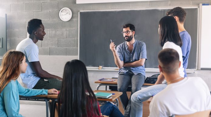 Teenager students and young male teacher sharing group discussion at School