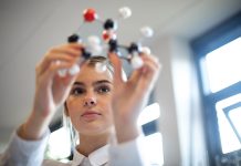 Reinventing the future of STEM for tomorrow’s jobs Close-up, shot through the hands of a female teenager examining a molecular chemistry set. She is wearing her school uniform.