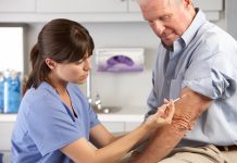 Doctor Giving Male Patient Injection In Hospital Room